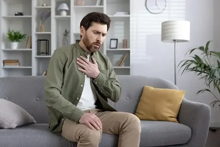 Man holding his chest experiencing chest pain symptoms needing evaluation by Dr. Fernandes in The Woodlands, TX